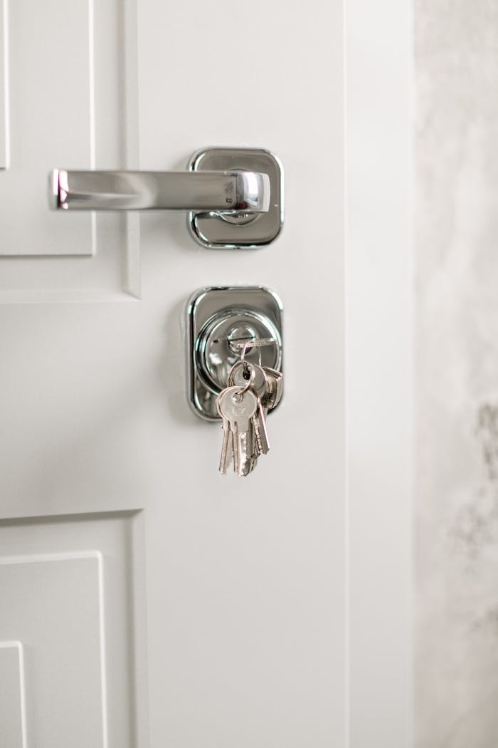 Close-up of a modern silver door handle with keys hanging in the lock, symbolizing security.